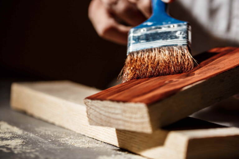 Applicazione di impregnante su tavola di legno durante il trattamento protettivo della superficie