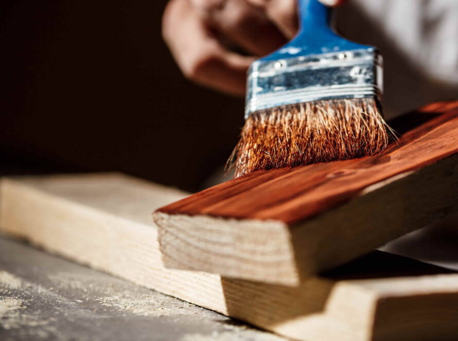 Applicazione di impregnante su tavola di legno durante il trattamento protettivo della superficie
